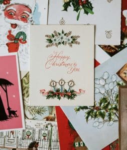 Last posting dates for Christmas chrsitmas co uk The last posting dates for Christmas: A selection of vintage-style Christmas cards arranged in a flat lay, with a central card reading “Happy Christmas to You” decorated with holly and candles.