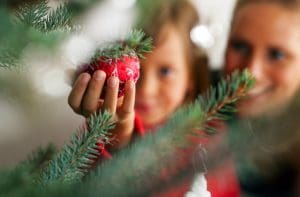 Woman and girl adding a bauble to a tree as part of Christmas decorating tips