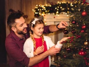 Dad and daughter learning about Christmas decoration tips with their tree