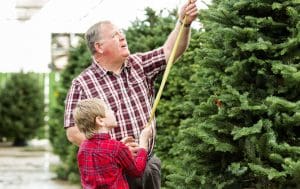 man and boy measuring a Christmas tree.