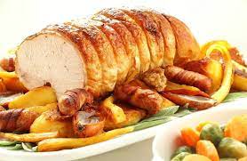 pic of a boneless turkey crown ready to be served up with potatoes and pigs in blankets