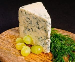pic of a block of cheese and grapes on a Xmas cheeseboard - Your guide to great Christmas cheeseboards 