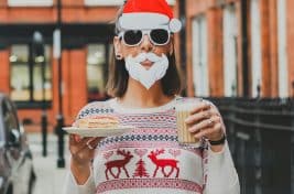 Pic of a woman dressed in a Santa mask and festive jumper to illustrate a story about Christmas clothing