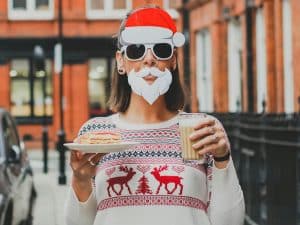 Pic of a woman dressed in a Santa mask and festive jumper to illustrate a story about Christmas clothing