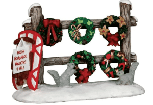 Lemax Caddington village Christmas wreaths sale pinned to a wooden fence