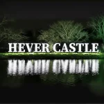 A lit sign for Hever Castle Christmas reflecting in the water