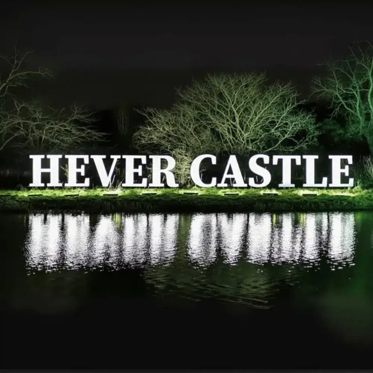 A lit sign for Hever Castle Christmas reflecting in the water