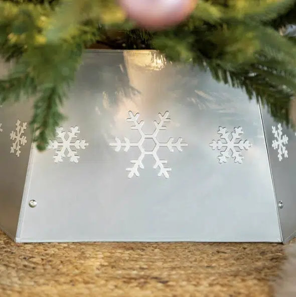 An elegant silver metallic Christmas tree skirt wrapped around a decorated evergreen base, shimmering under festive lights for a modern festive touch.